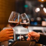 Two bartender enjoying of Cheers glass of wine for wine tasting event in a restaurant at sunset.